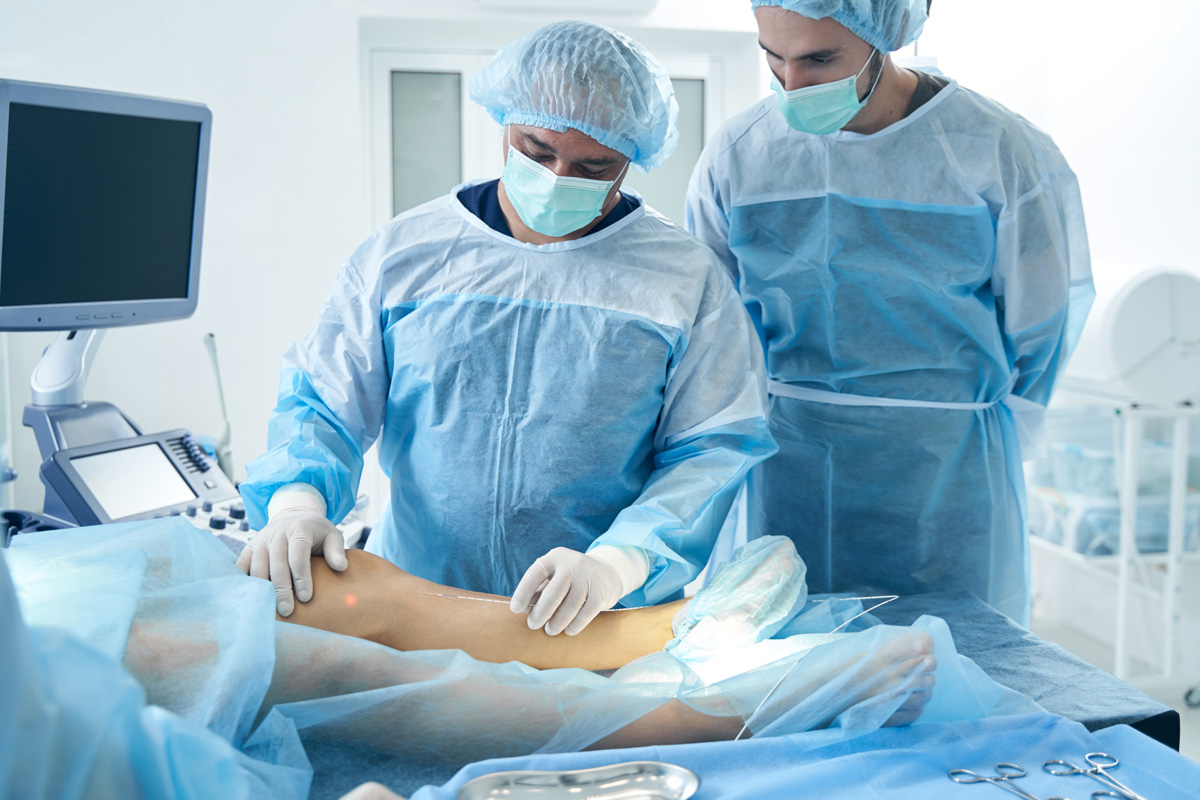 Two vascular surgeons performing a procedure on a patient’s leg in El Paso.